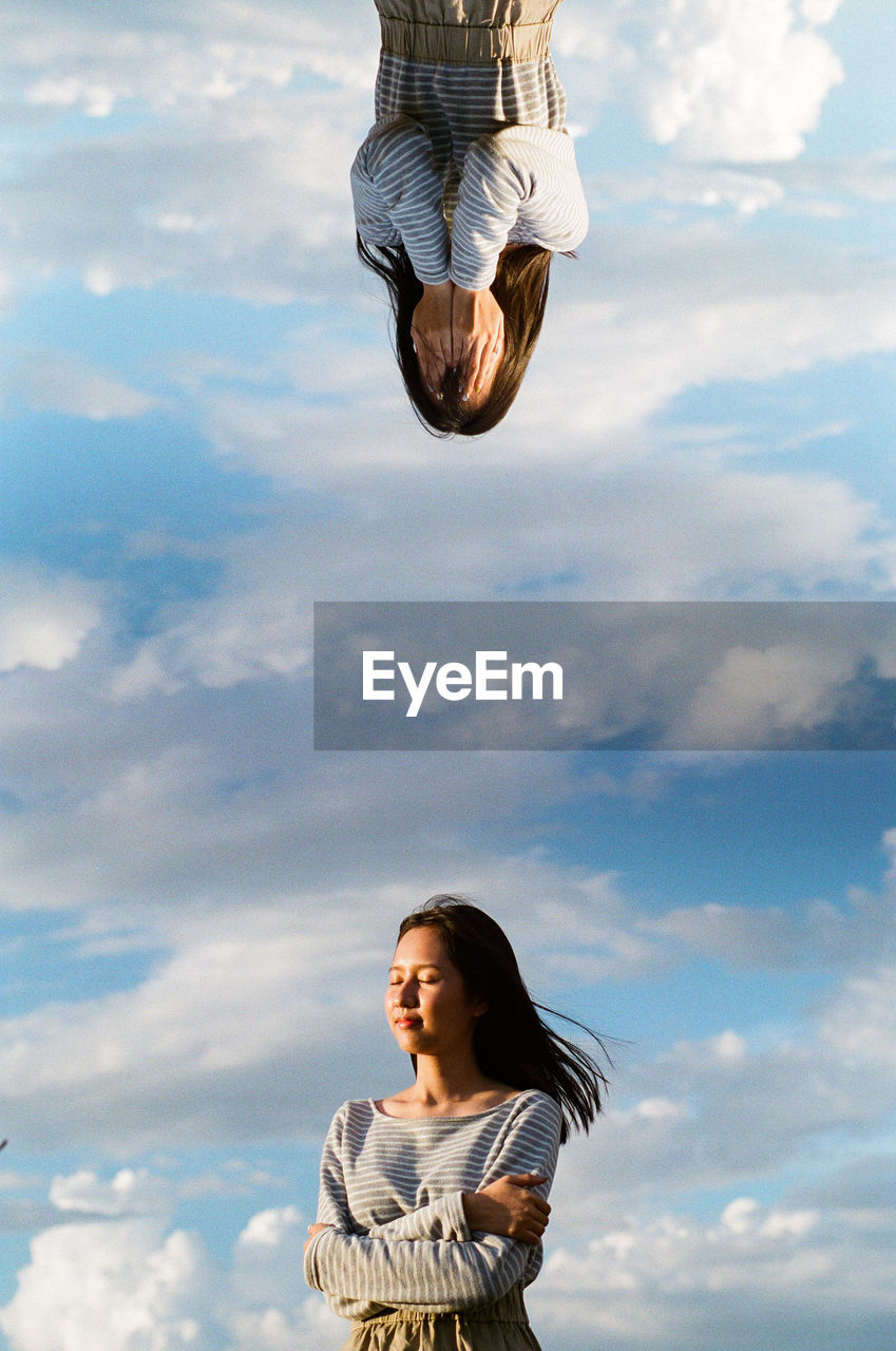 LOW ANGLE VIEW OF YOUNG WOMAN AGAINST SKY