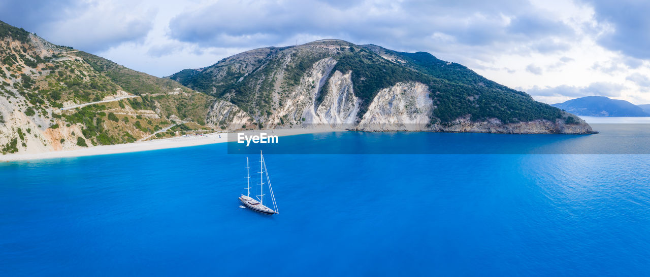 SAILBOAT IN SEA AGAINST MOUNTAIN