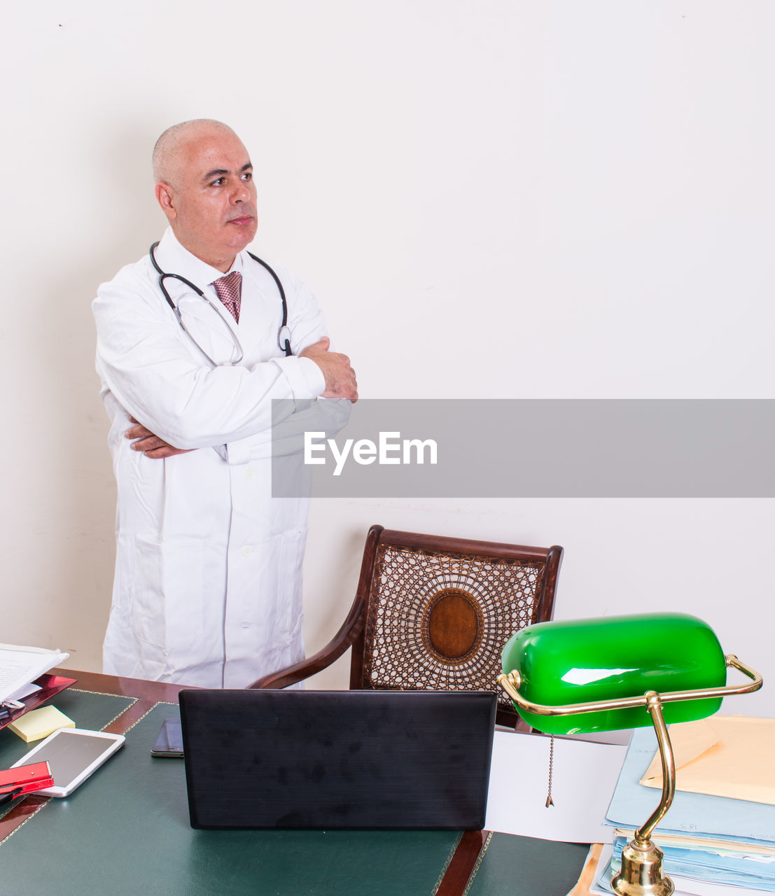 Male doctor with arms crossed standing in medical clinic