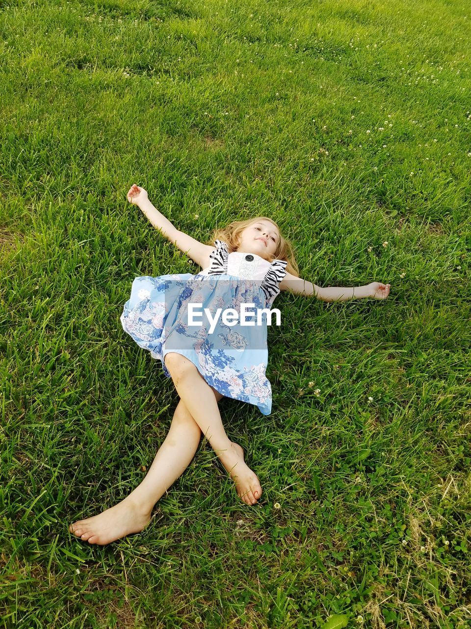 High angle view of carefree girl lying on grassy field