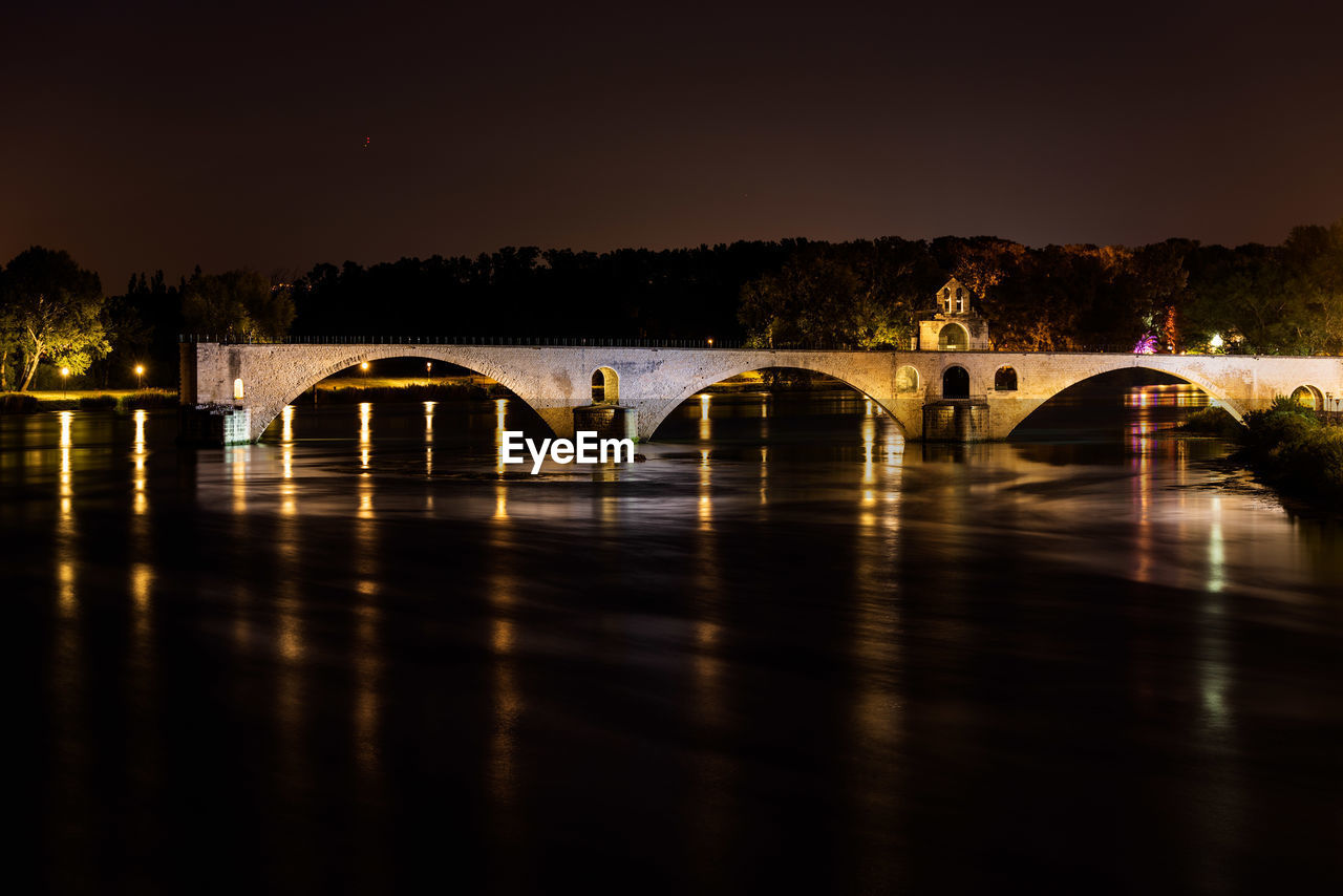 Arch bridge over river against sky at night