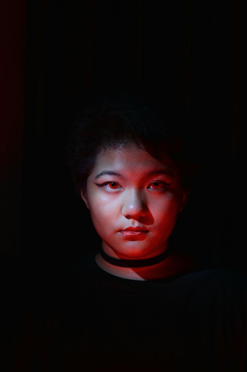 Low lit portrait of a young girl with colored light as accent