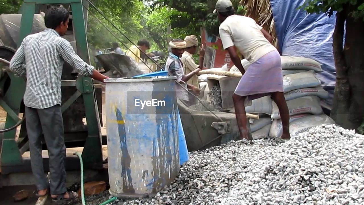 REAR VIEW OF PEOPLE WORKING AT BUS BY WATER