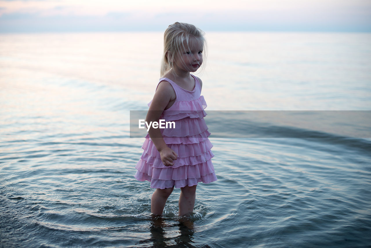 Girl standing in sea against sky