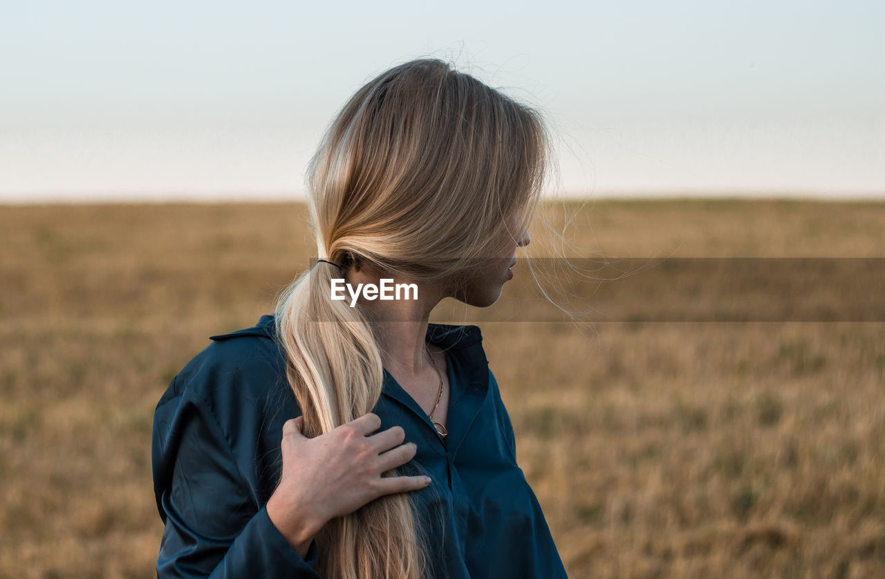 Woman looking away while standing on land against sky