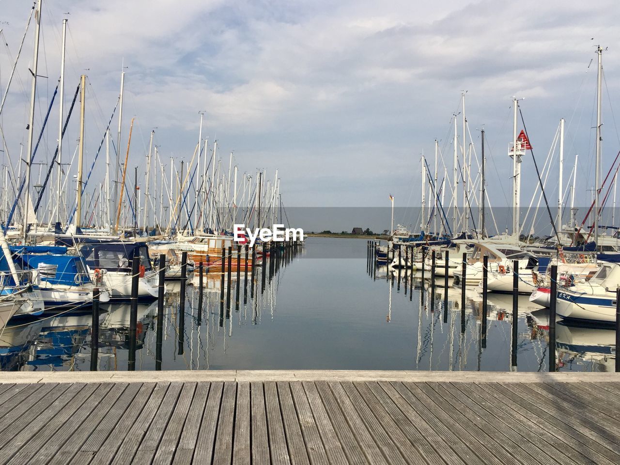 Sailboats moored in harbor against sky