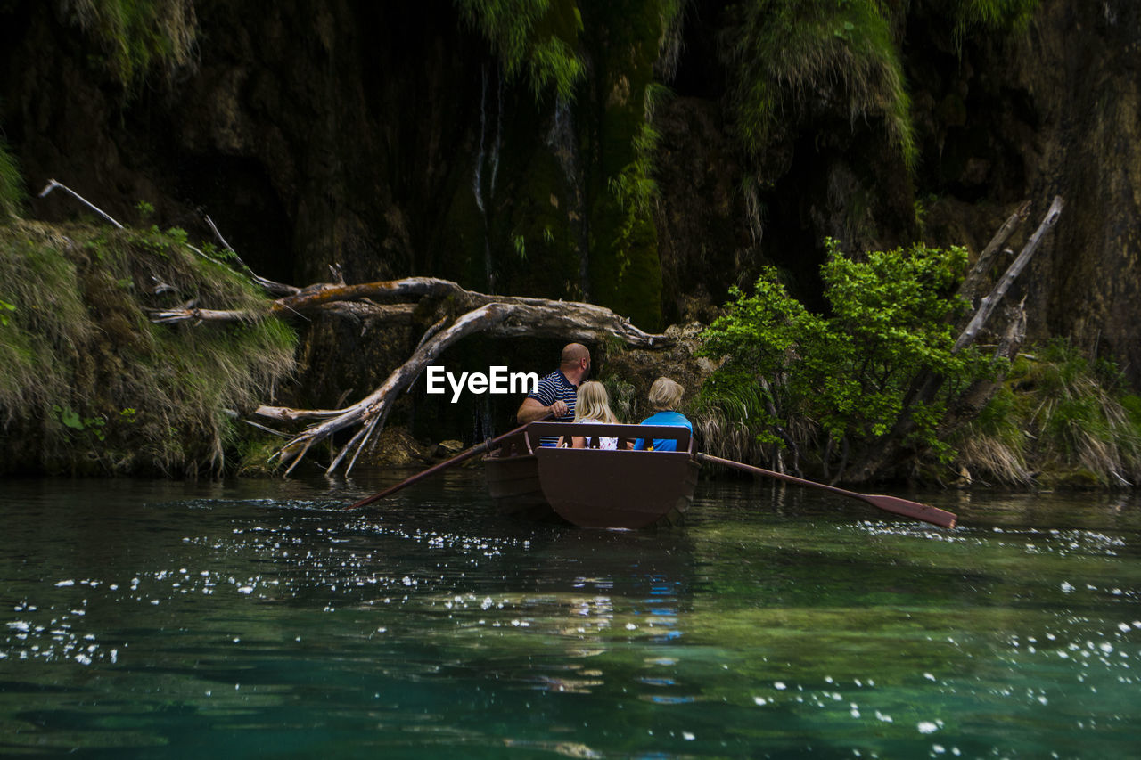 MAN IN RIVER BY TREES IN FOREST