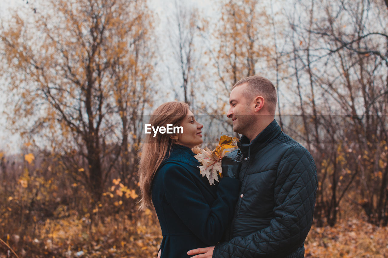 Young man and woman standing against trees