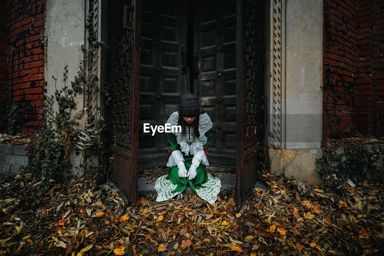 Woman in halloween costume standing by abandoned building