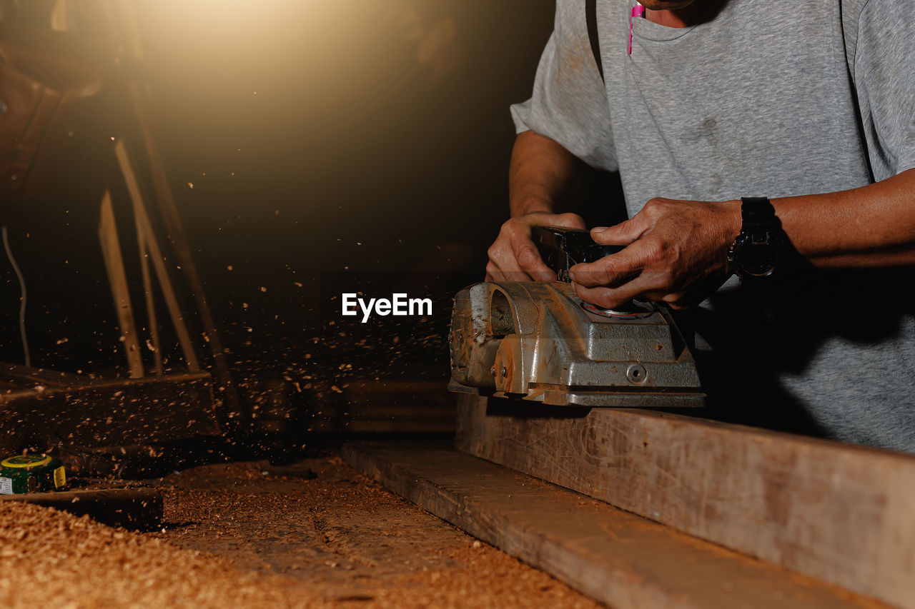 Close-up of a carpenter using a circular saw or a tool to cut wooden planks to make furniture  