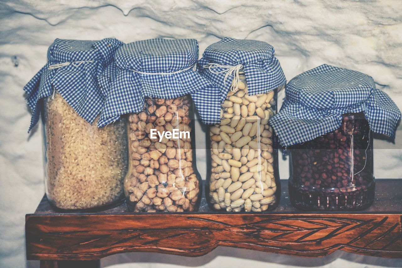 Grains in glass jars on table by wall