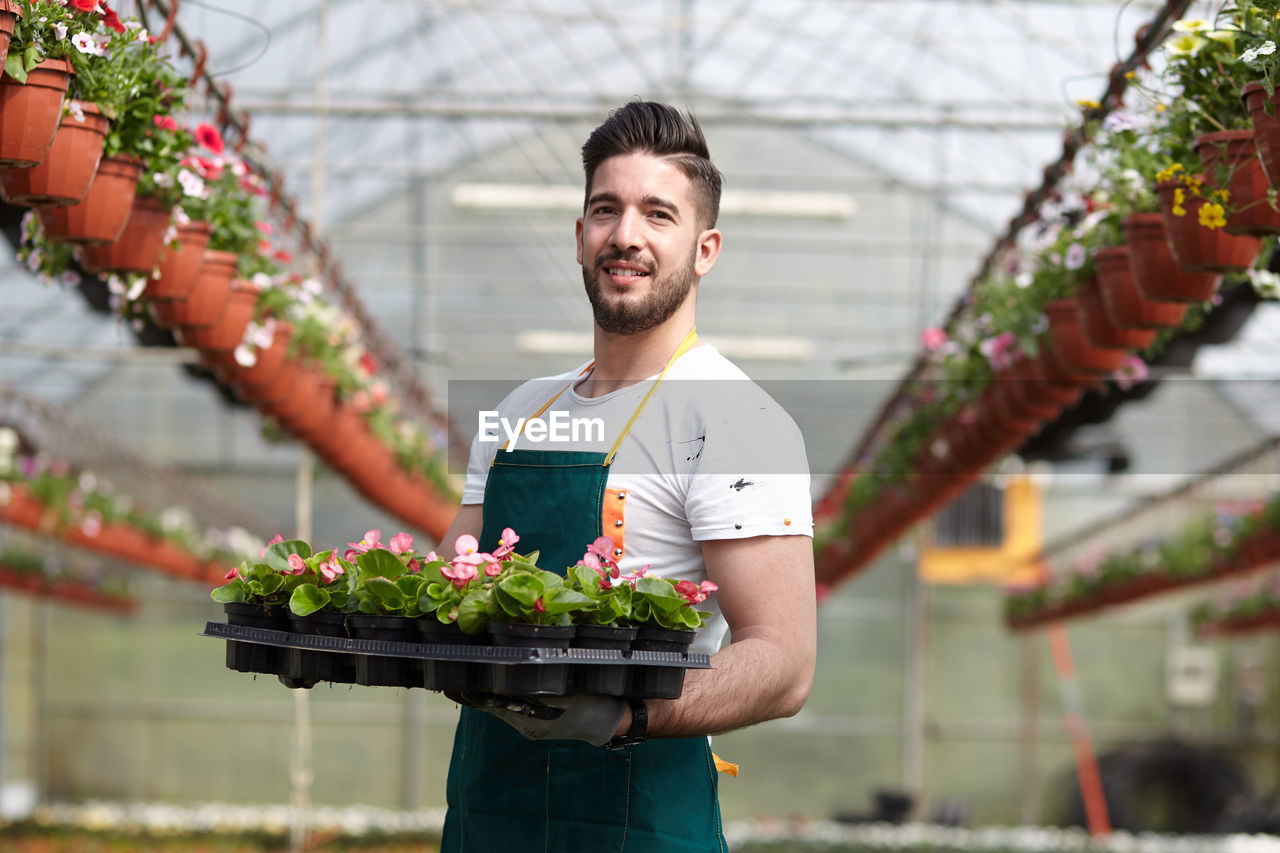 Young man smiling while standing in greenhouse