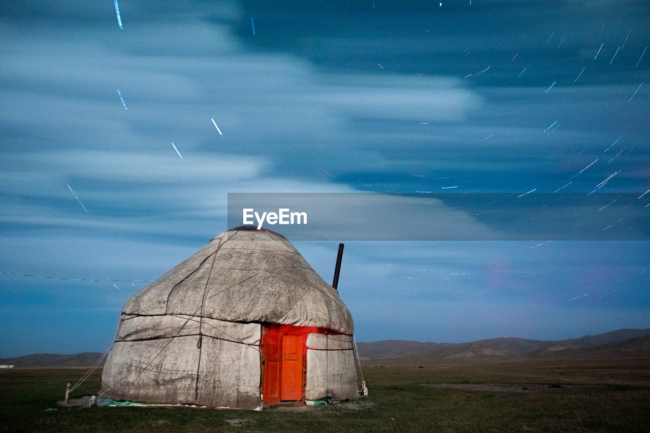 Yurt on field against sky at dusk