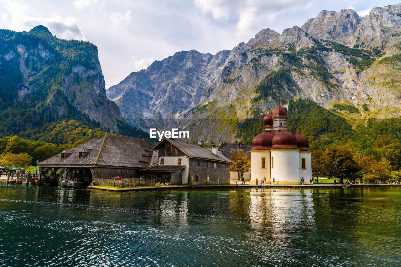 Built structure by lake and mountains against sky