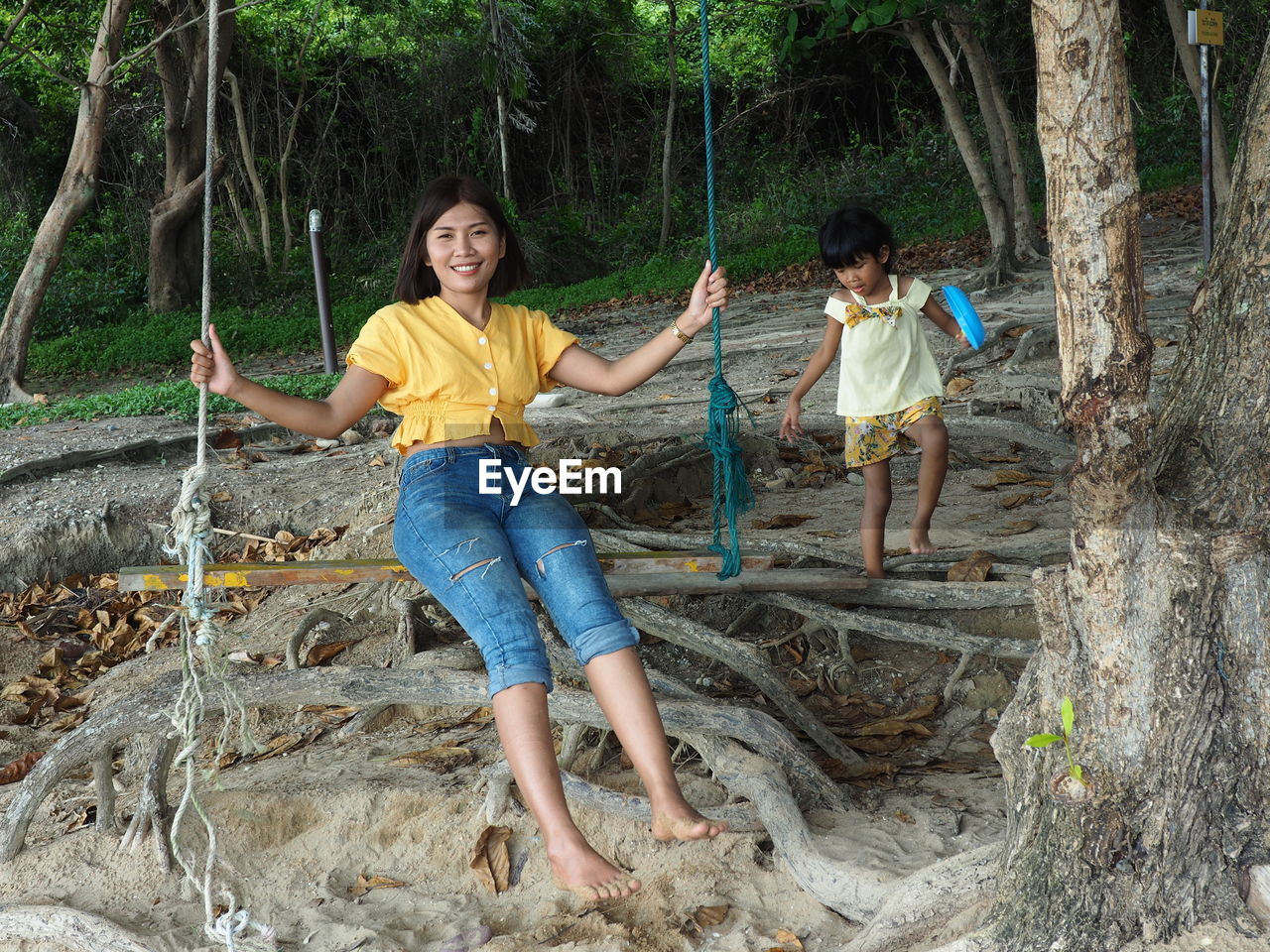 Portrait of woman sitting swing by daughter