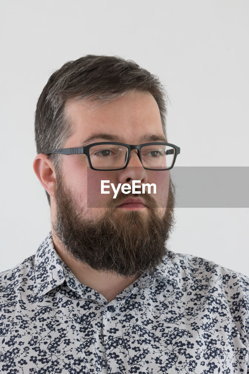 Bearded man wearing eyeglasses against white background