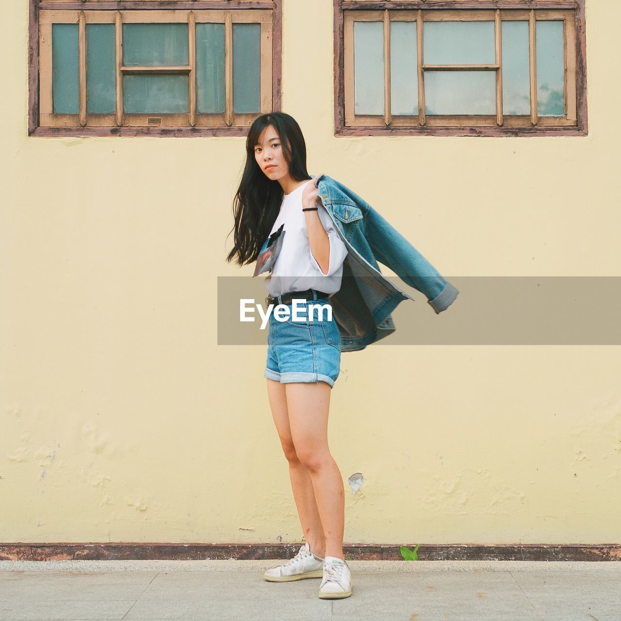 Portrait of young woman standing against building