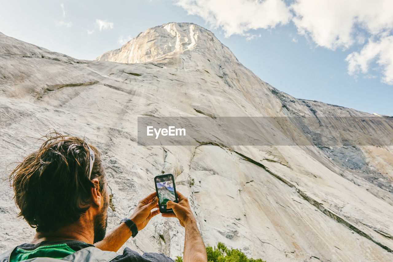 Young man taking picture of el capitan mountain in yosemite park.