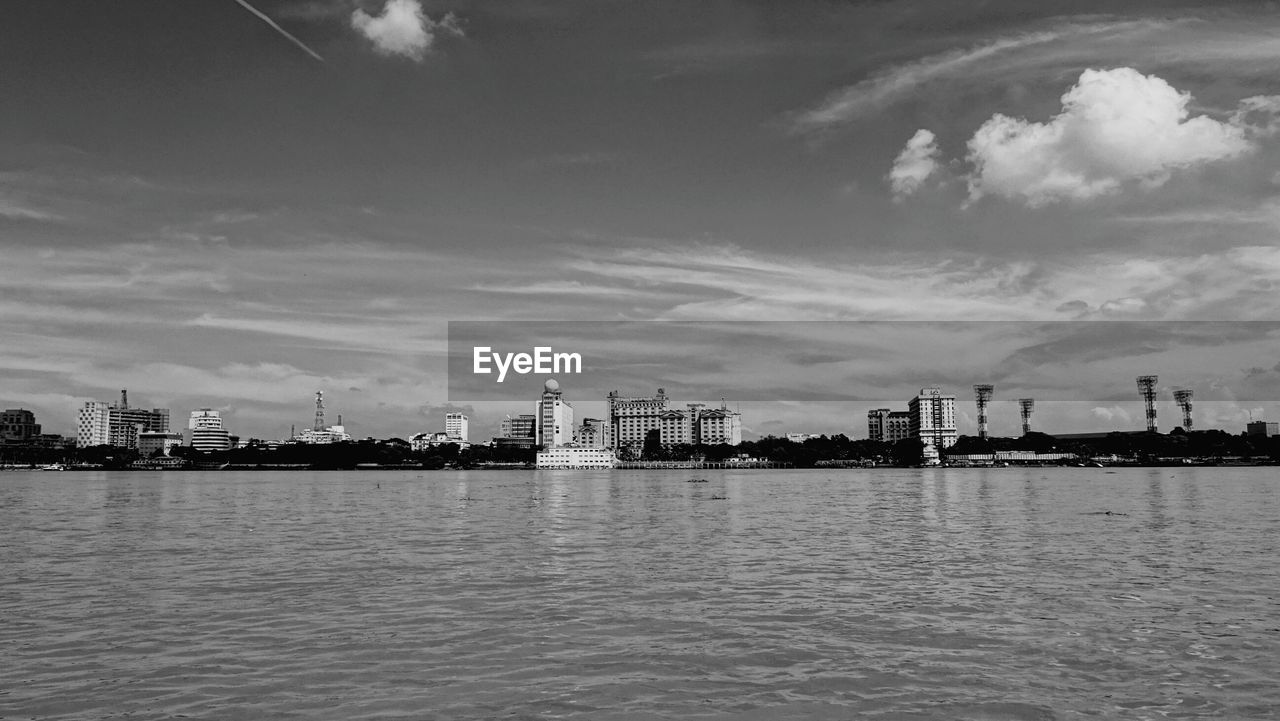 Scenic view of river by city against sky