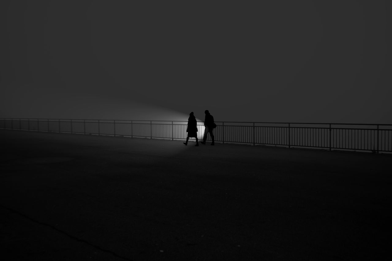 Silhouette people walking on bridge against clear sky