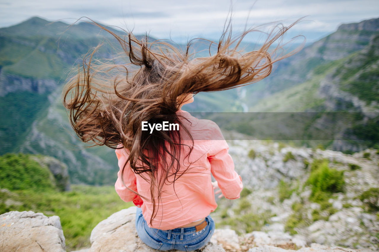 Young woman looking at mountain against sky