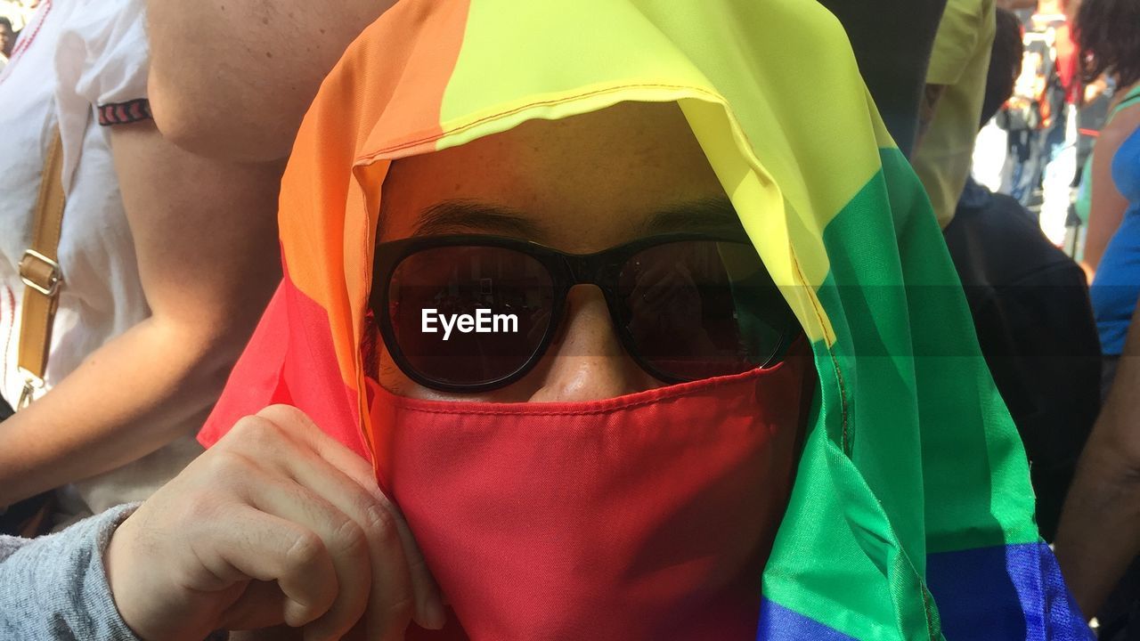 Man covering face with rainbow flag