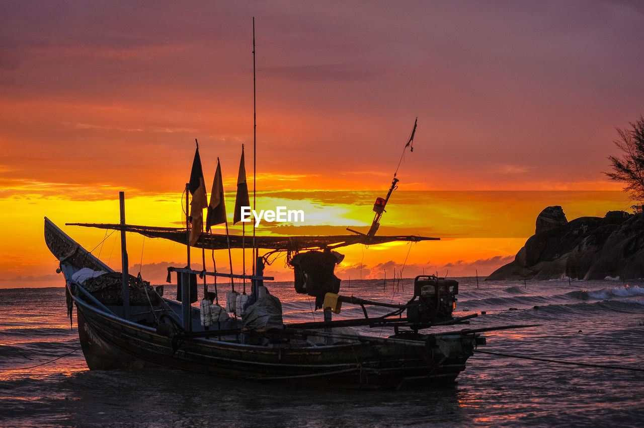 Boat in sea against orange sky