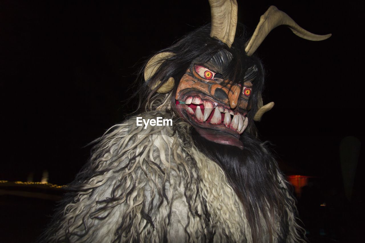 Portrait of man wearing mask against black background