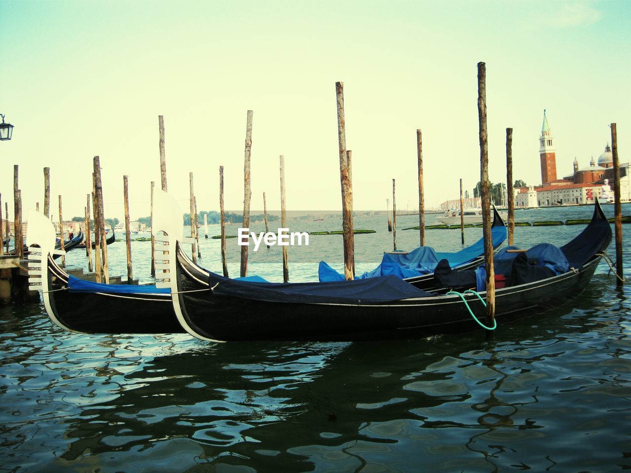 BOATS MOORED ON WOODEN POST IN SEA AGAINST SKY