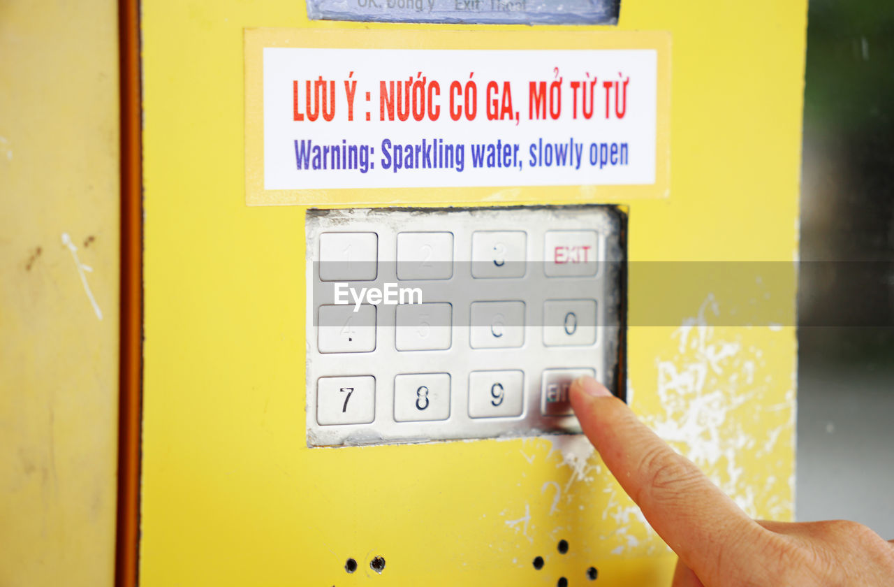 Cropped finger pressing on vending machine number pad to order drinks