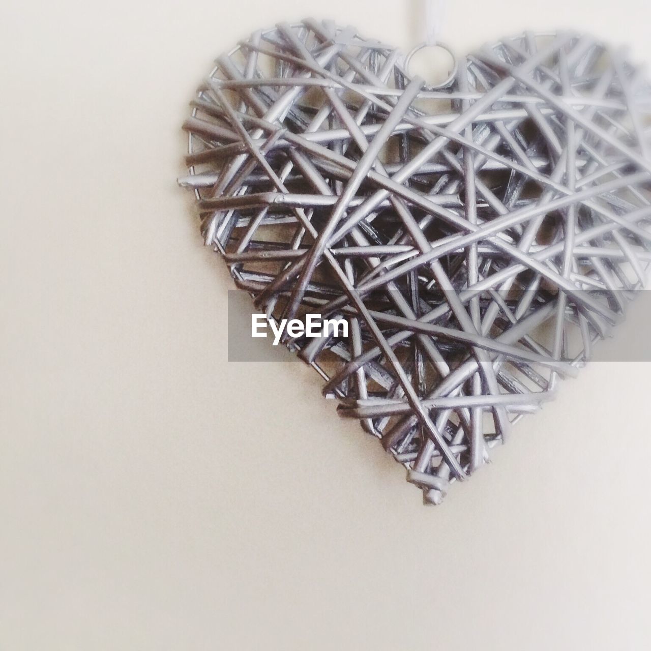 Close-up of woven metallic heart shape hanging against wall