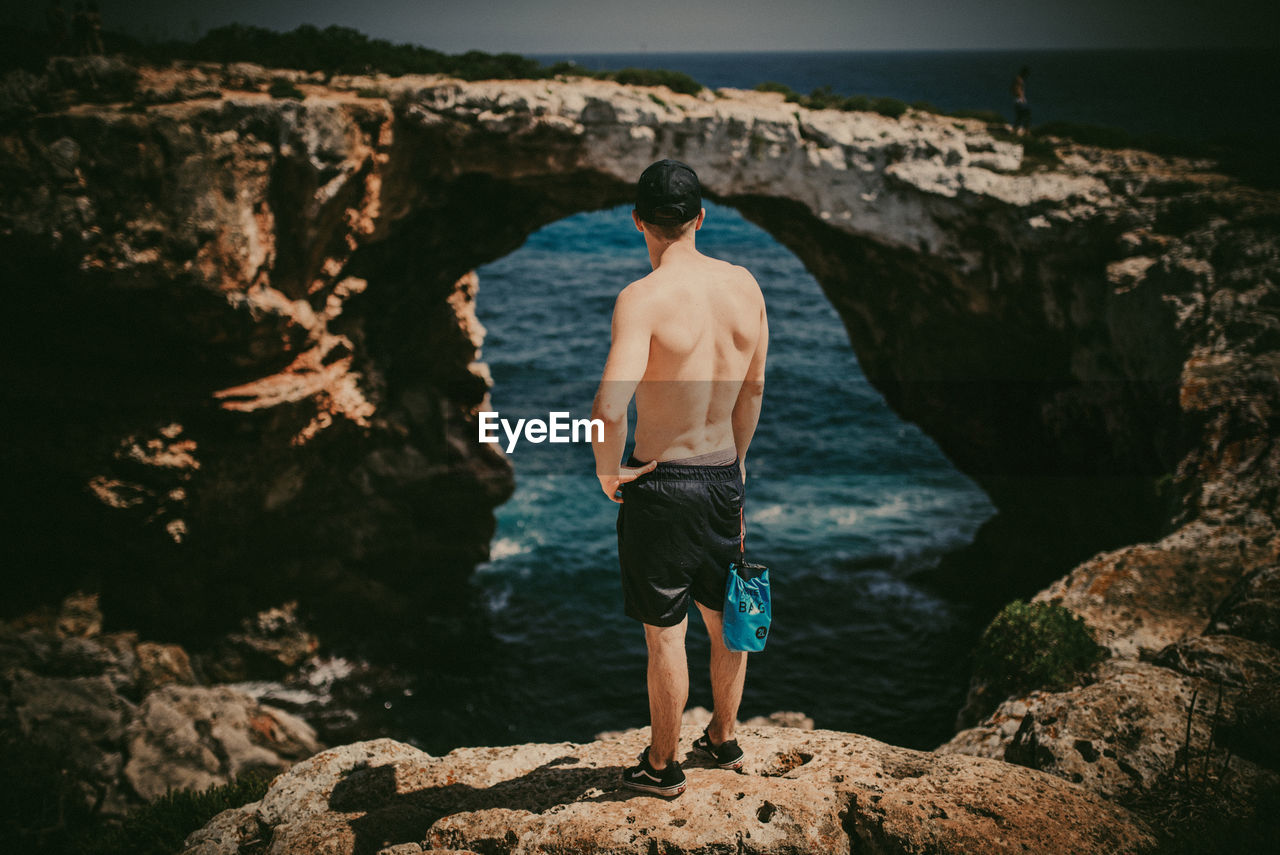 Rear view of shirtless man on shore