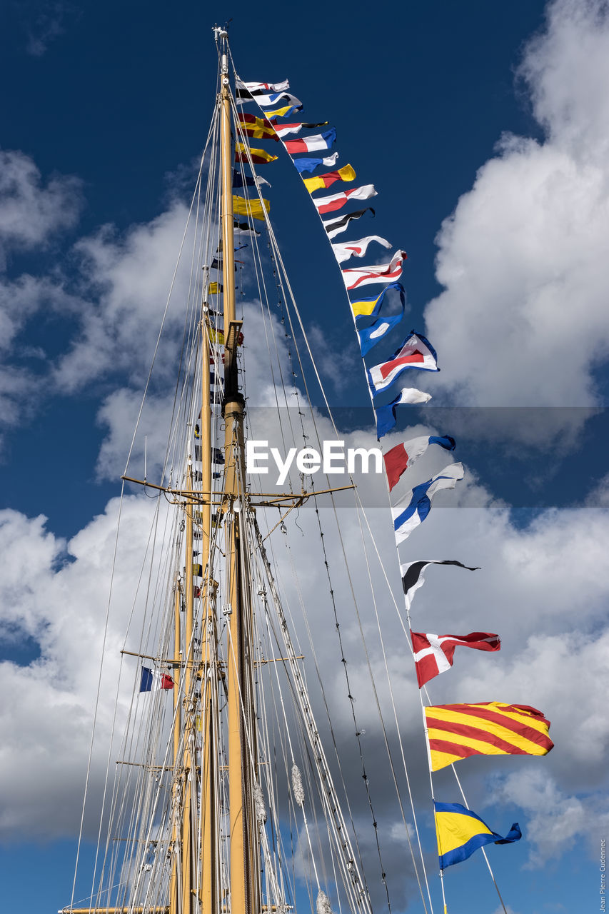 Low angle view of various flags on mast against cloudy sky