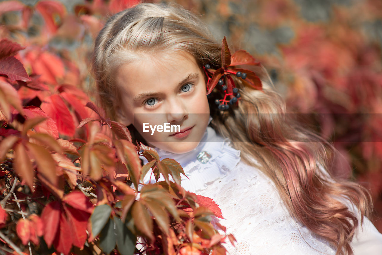 Portrait of cute girl by leaves during autumn