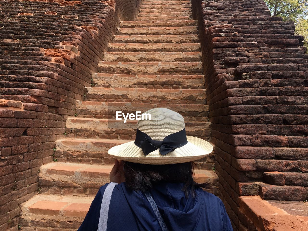 REAR VIEW OF WOMAN ON STEPS AGAINST WALL