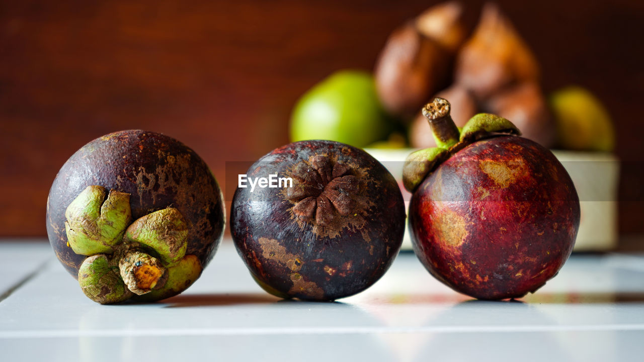 CLOSE-UP OF APPLES ON TABLE AGAINST BLURRED BACKGROUND