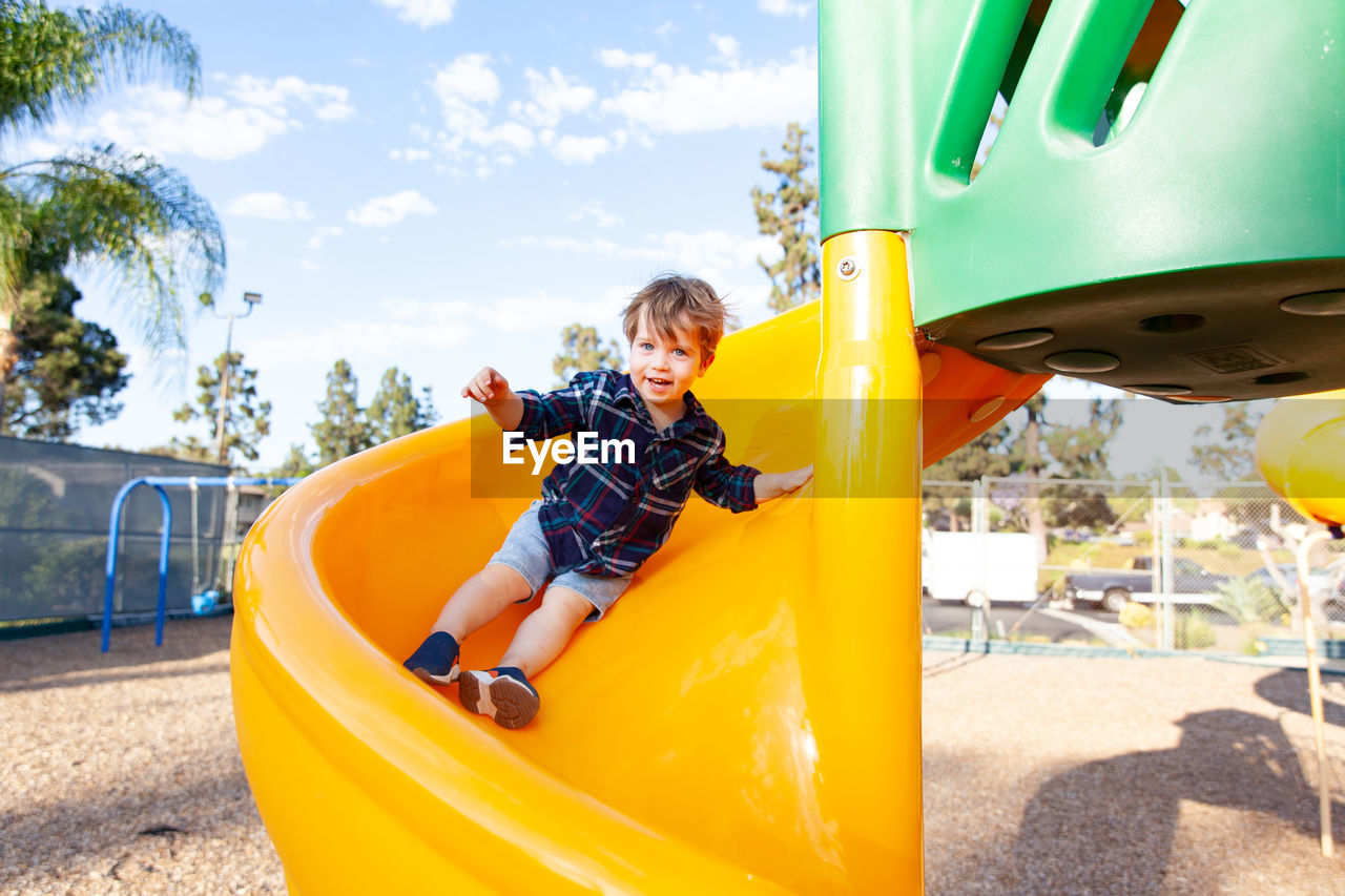 Modern colorful kids playground - swings, slides, steps and ladders. little boy on swing and slide.