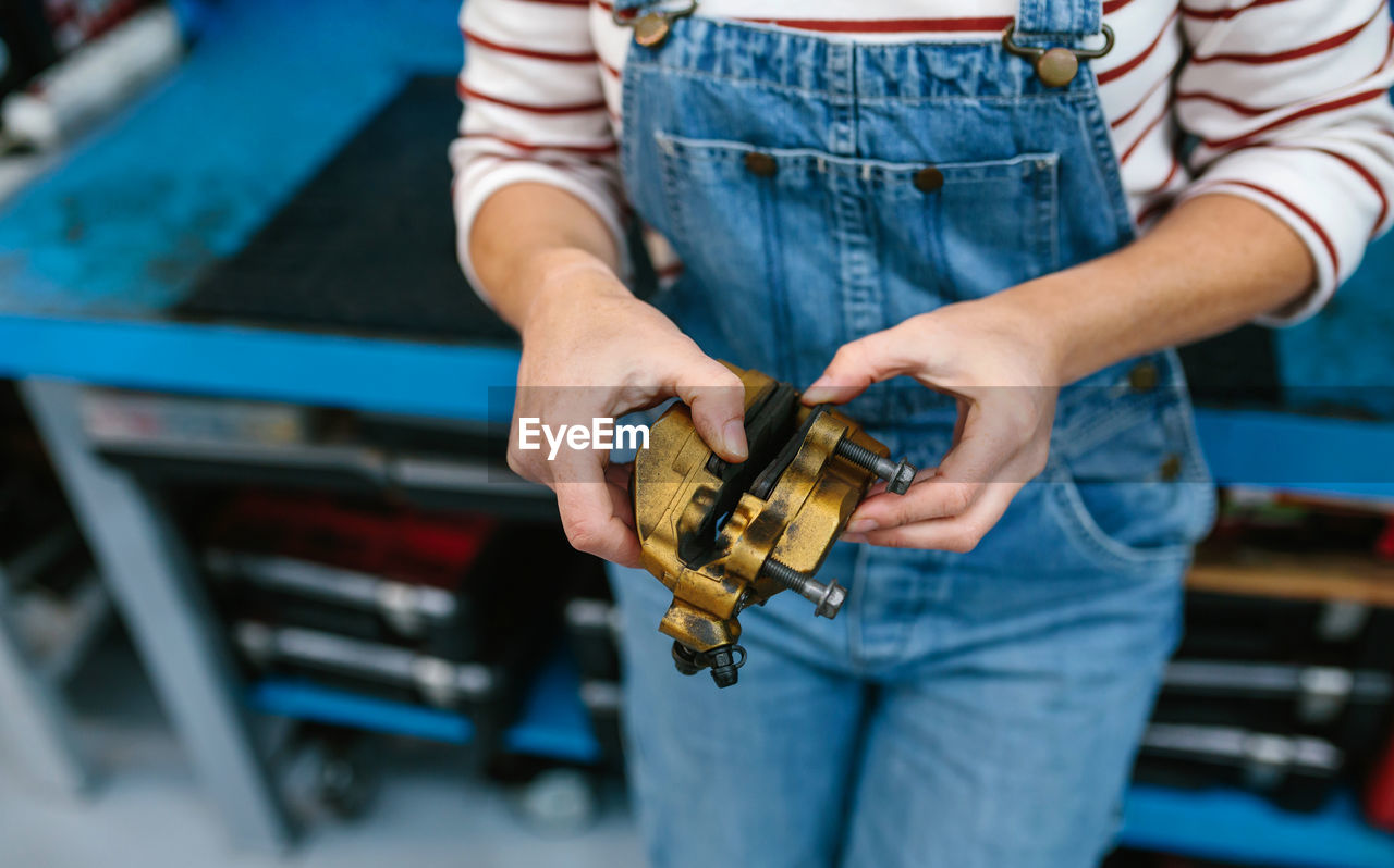 Mechanic woman checking caliper brake system in front of workbench