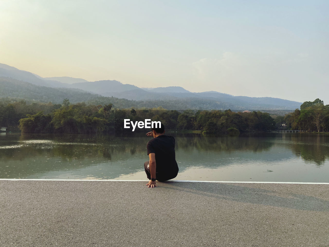 REAR VIEW OF BOY LOOKING AT LAKE AGAINST MOUNTAIN