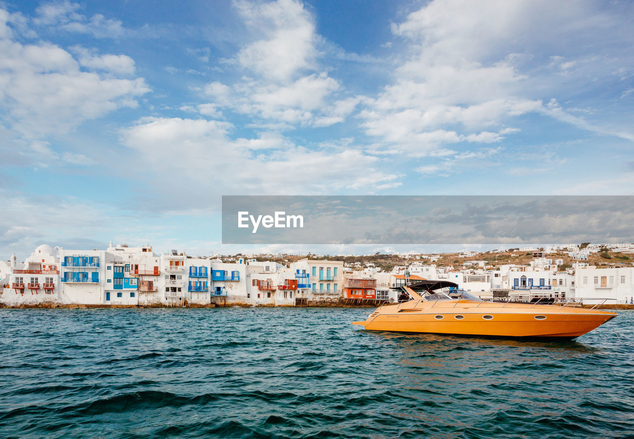 BOATS IN SEA BY BUILDINGS AGAINST SKY