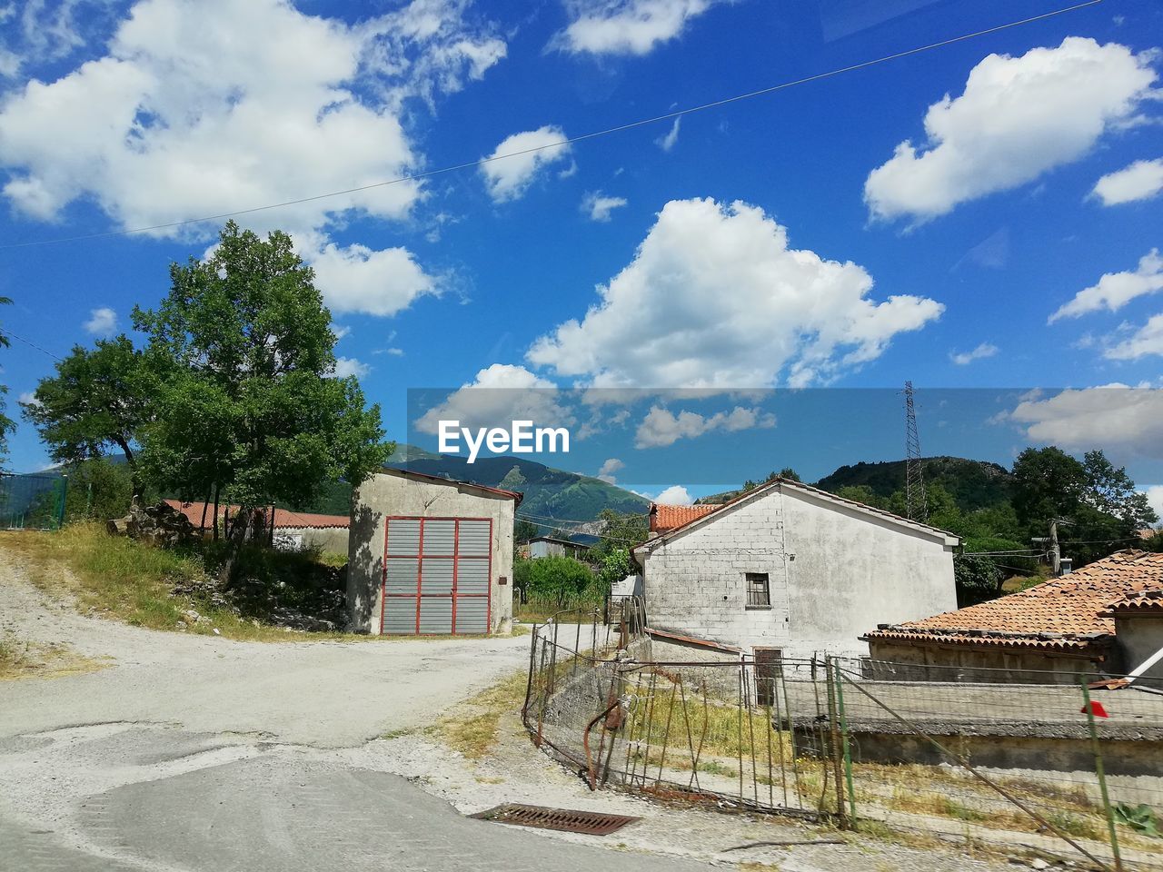 HOUSES BY ROAD AGAINST SKY