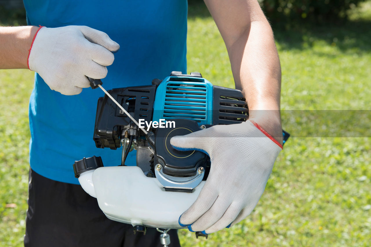 The man cutting a grass with the lawn mower. closeup