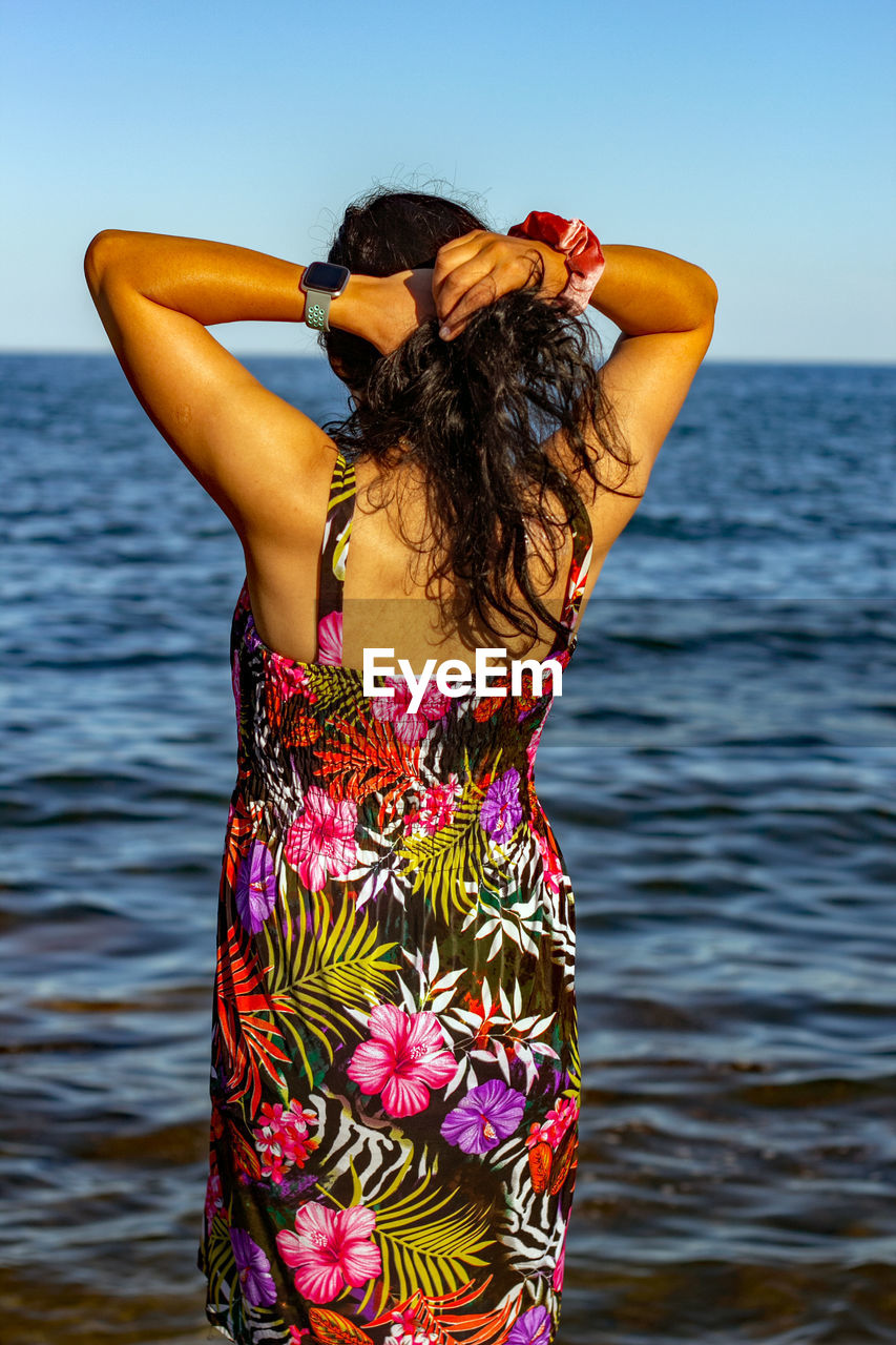 Midsection of woman standing by sea against sky