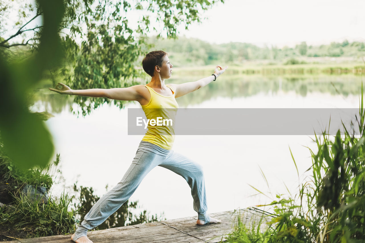Young smiling woman practice yoga outdoors. new normal social distance. physical and mental health