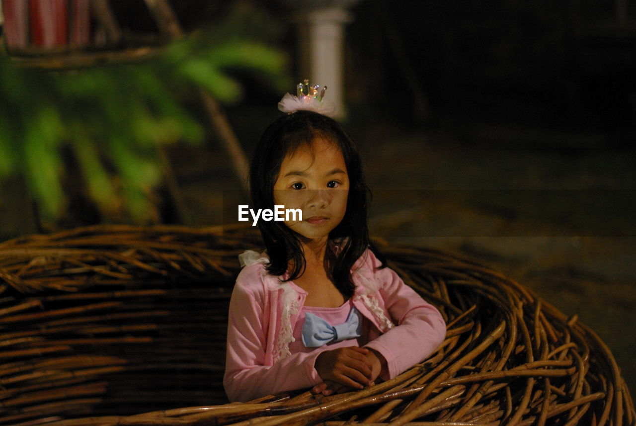 Portrait of cute girl standing by wicker nest