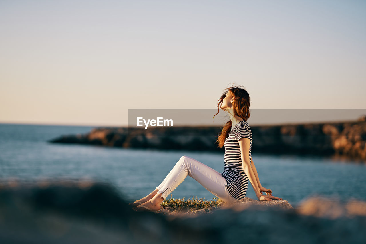 WOMAN LOOKING AT SEA AGAINST SKY