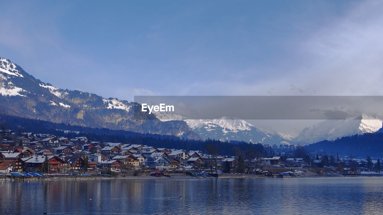 SCENIC VIEW OF TOWNSCAPE BY RIVER AGAINST SKY