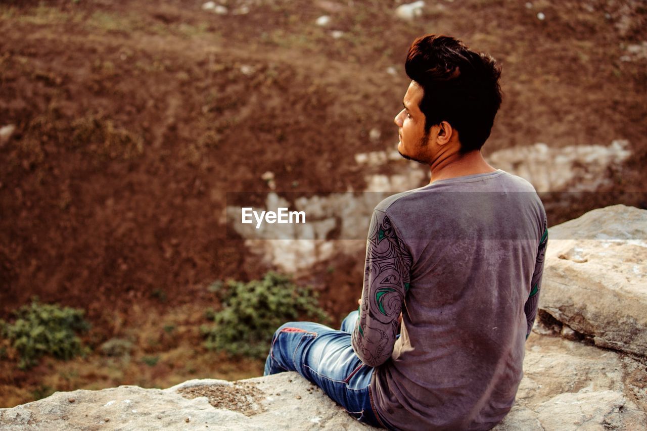 Rear view of young man looking away on land