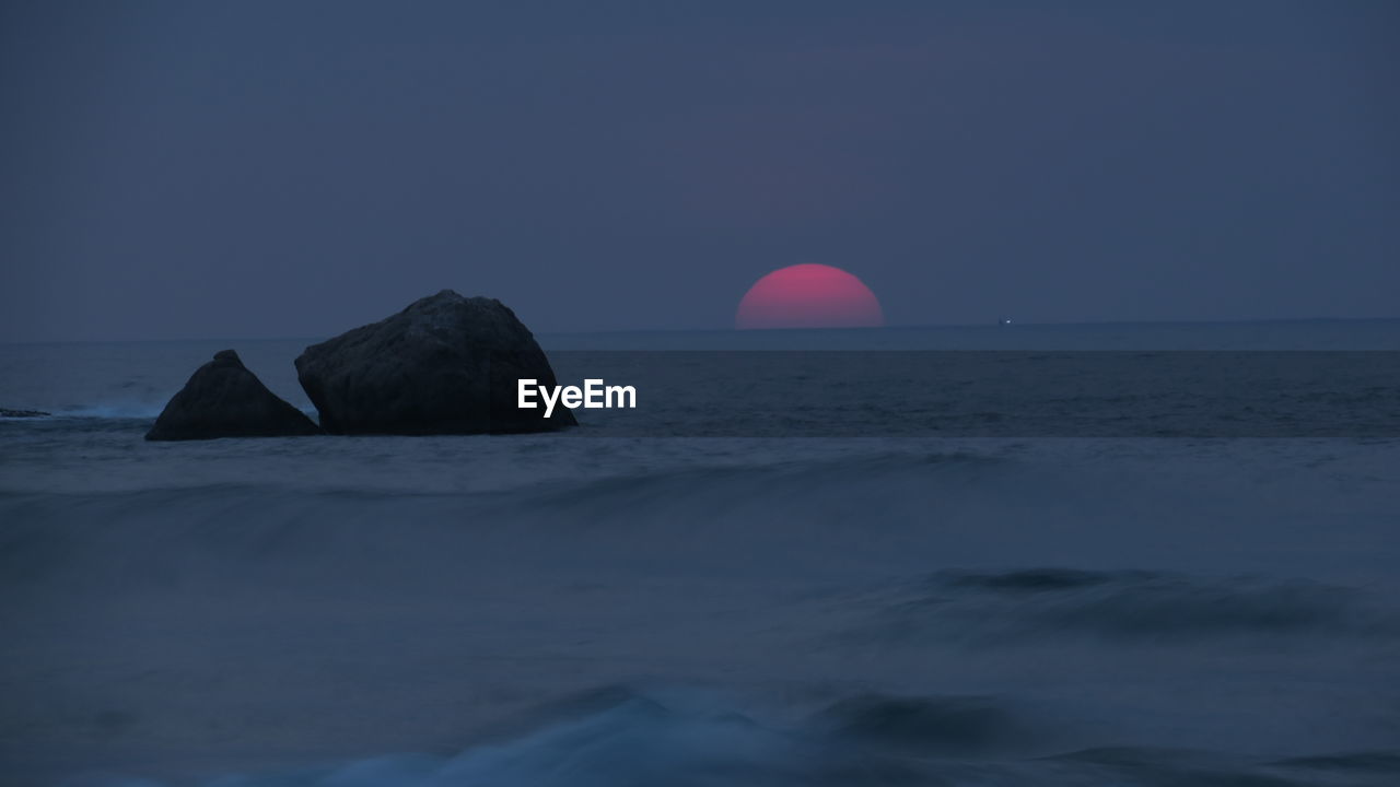 Scenic view of rocks in sea against sky