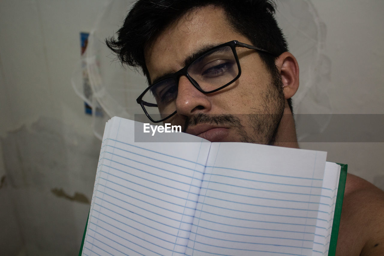 A young man with a paper notebook resting on his face